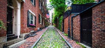 波士顿比肯山，一条长满青苔的鹅卵石街道两旁排列着红砖房屋